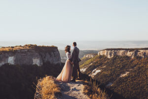 Bride and groom walking in mountains at sunset. Around the stunning scenery with views of the mountains and canyon Mangup