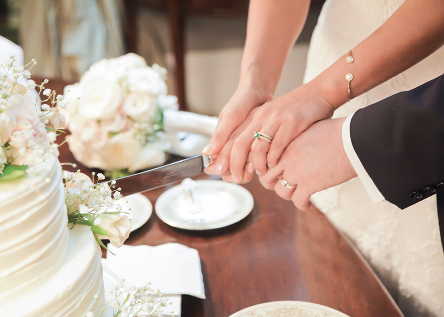 Couple's hands cutting their wedding cake.