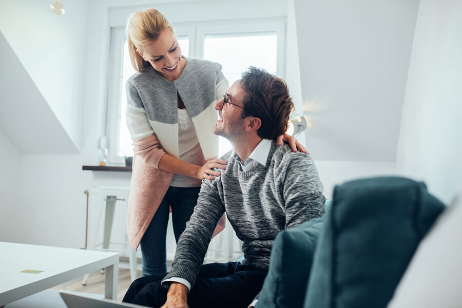 Young woman standing by a male who is using a laptop