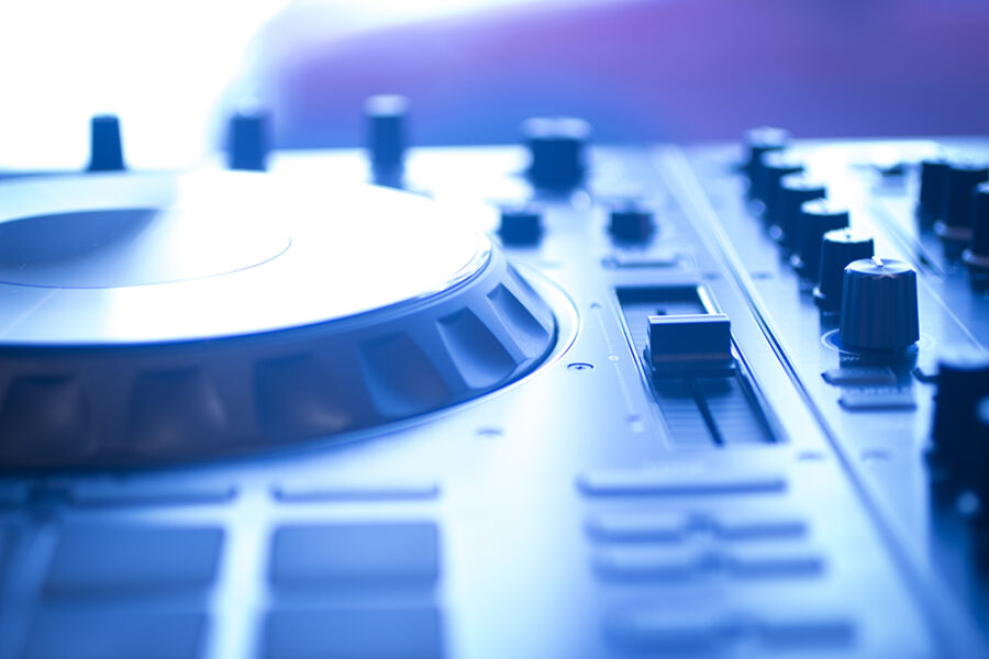 DJ console cd mp4 deejay mixing desk Ibiza house techno dance music wedding reception party in nightclub with colored lighting effect disco lights.