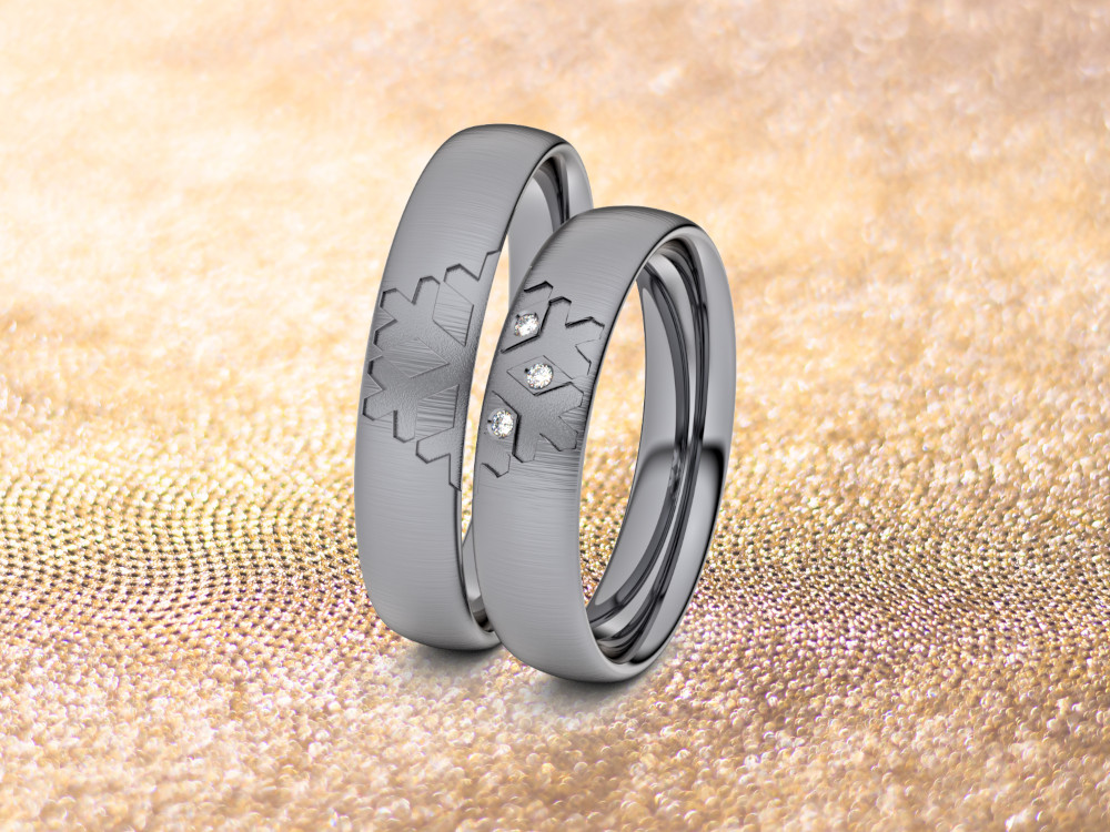 Ein Paar Ringe aus Tantal auf strukturiertem, funkelndem Goldgrund. Ein Ring weist ein Sternenmuster auf, während der andere mit drei kleinen Diamanten in einem ähnlichen Sternenmuster verziert ist.