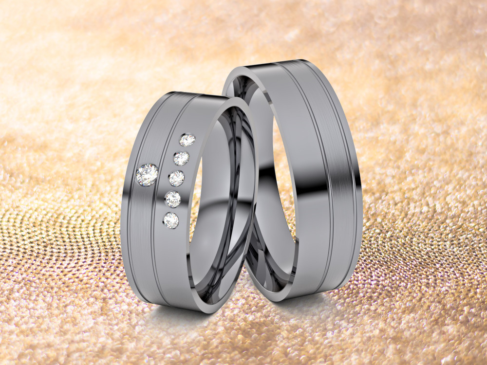 HOCHZEITde-Inspriation-Ratgeber-Ringe-Schmuck-Trauringe-aus-Tantal-vonjacob-sechs-Diamanten Zwei Eheringe aus Tantal werden auf einer strukturierten, goldenen Oberfläche präsentiert. Ein Ring ist mit fünf kleinen Diamanten verziert, während der andere ein schlichtes Design hat.